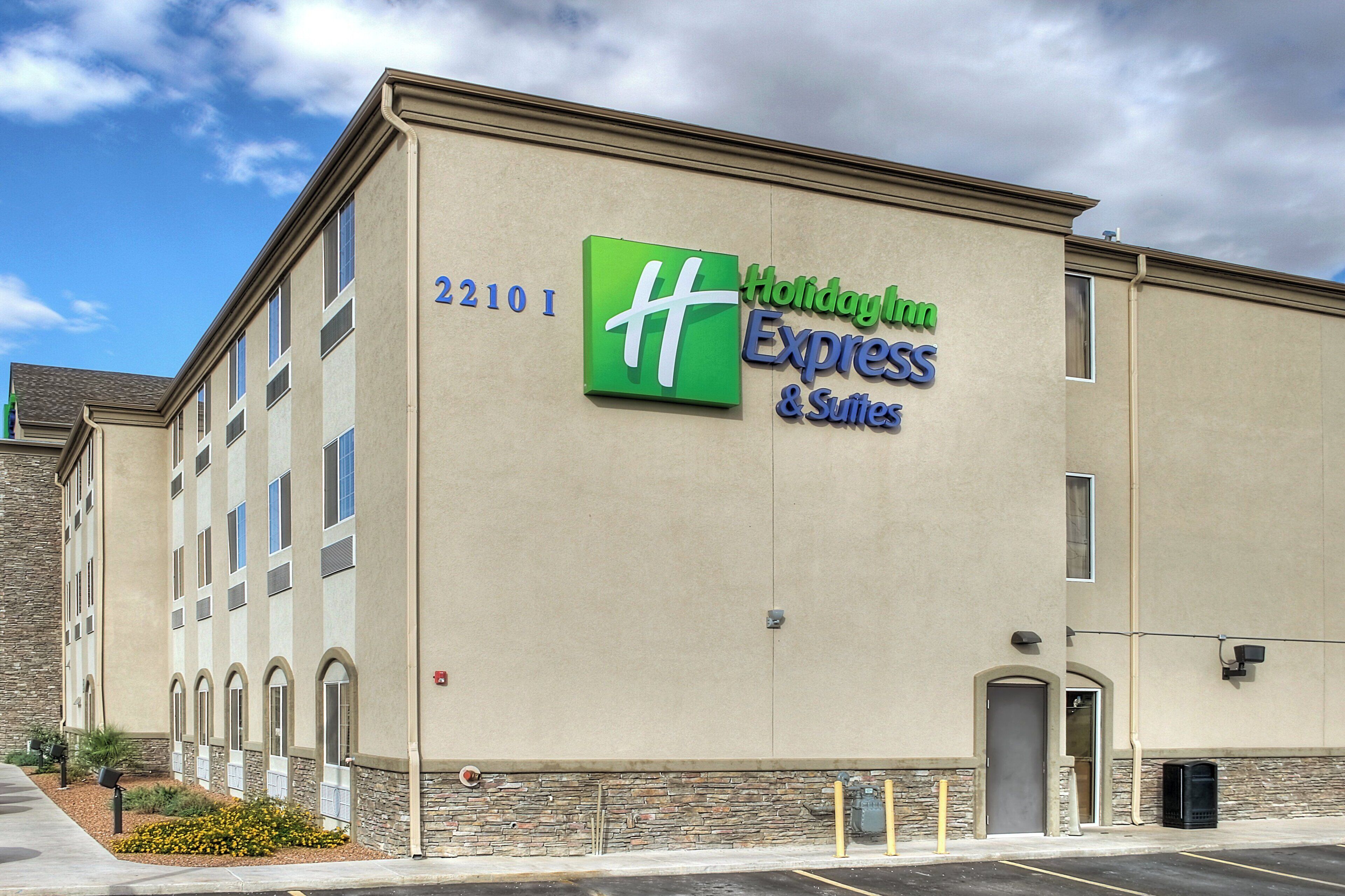 A Holiday Inn Express & Suites building with a stone facade, numbered 2210, and a clear sky in the background.