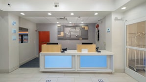 A reception area with a modern design, including a reception desk, a digital display, and a wall-mounted sign. - Holiday Inn Express Carlsbad by IHG (Carlsbad)