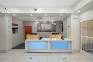 A reception area with a modern design, including a reception desk, a digital display, and a wall-mounted sign. - Holiday Inn Express Carlsbad by IHG (Carlsbad)