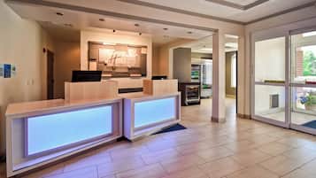 Et moderne receptionsområde med reception, et vægmonteret skilt og et køleskab fyldt med drikkevarer.