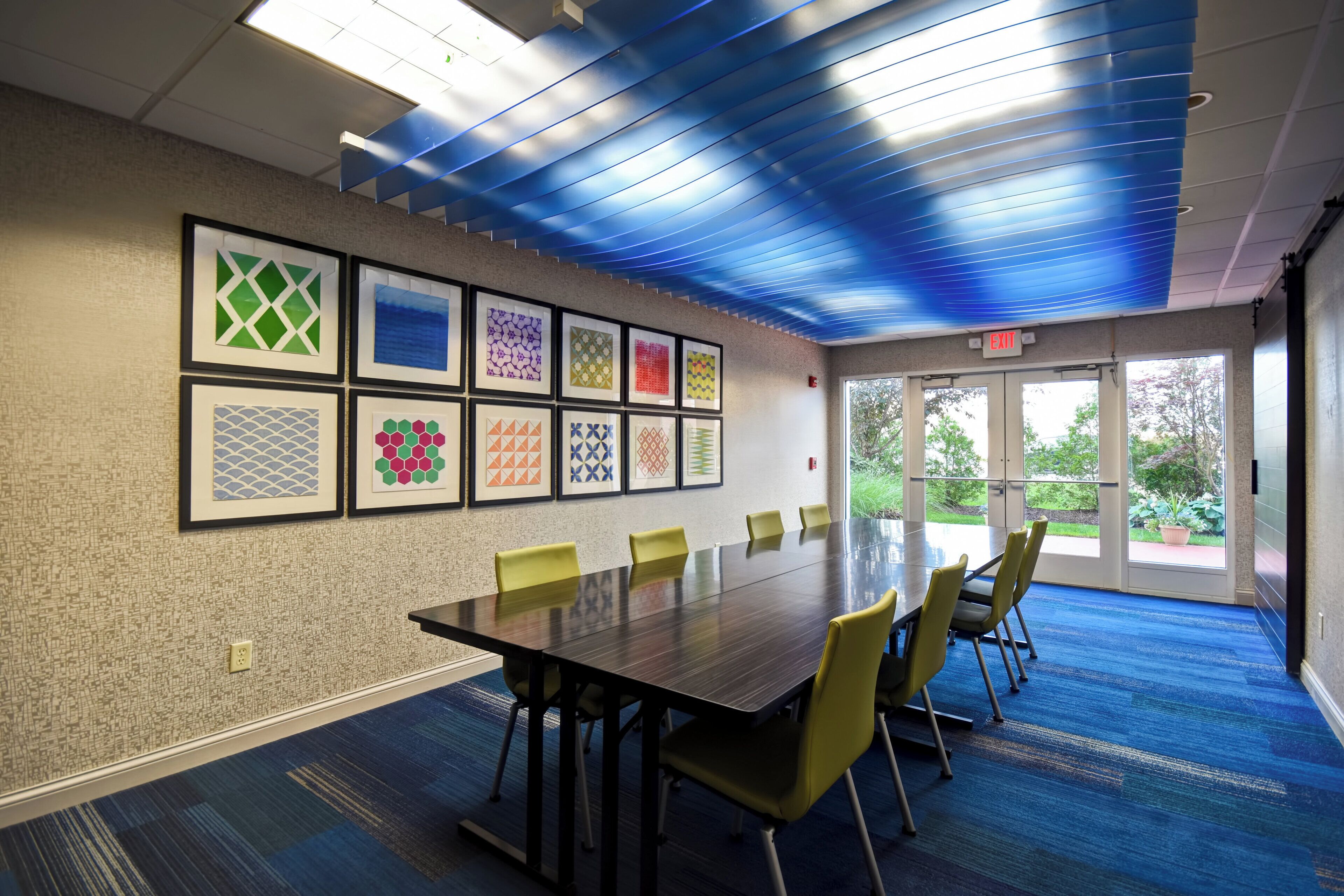 A conference room with a long table, yellow chairs, and framed artwork on the wall.