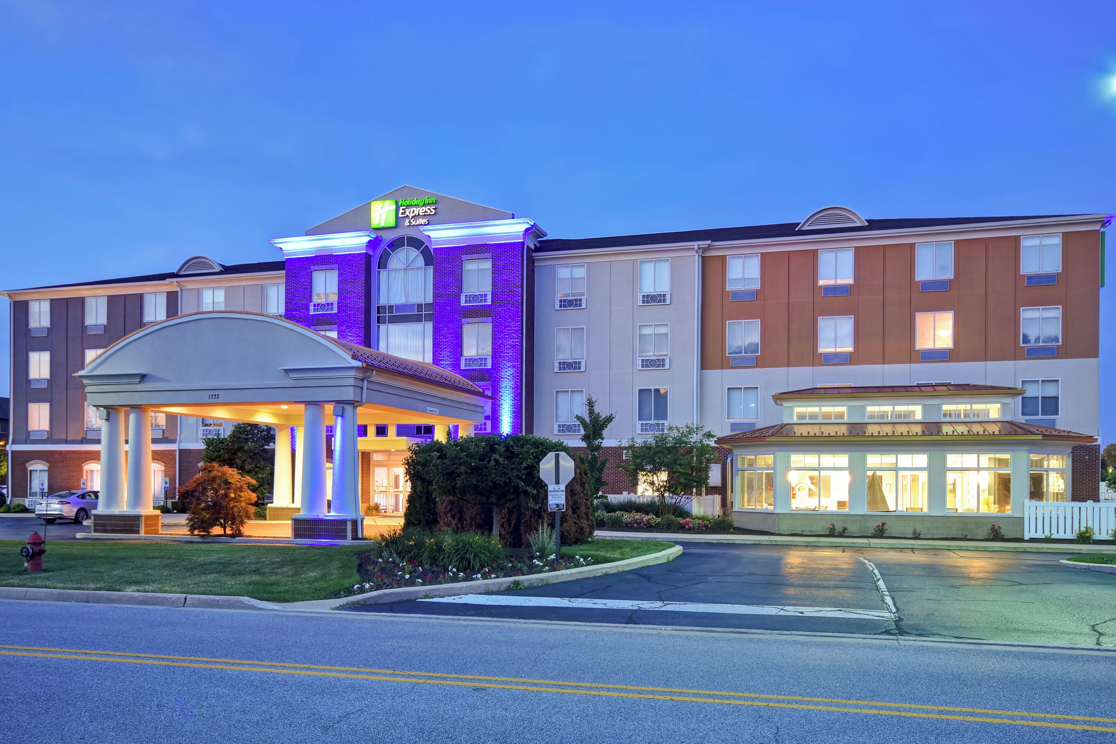 A hotel with a prominent entrance, a covered waiting area, and a well-lit facade.