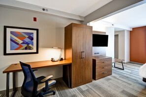 A modern hotel room with a wooden desk, a chair, a wardrobe, a flat-screen TV, and a framed abstract painting. - Holiday Inn Express & Suites Schererville by IHG (Schererville)