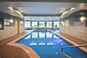 An indoor swimming pool with clear water, surrounded by seating areas and windows. - Holiday Inn Express & Suites Schererville by IHG (Schererville)