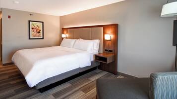 A hotel room with a bed, bedside table, lamp, and a framed picture on the wall.