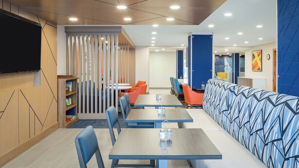 Un comedor moderno con mesas, sillas y un largo banco.