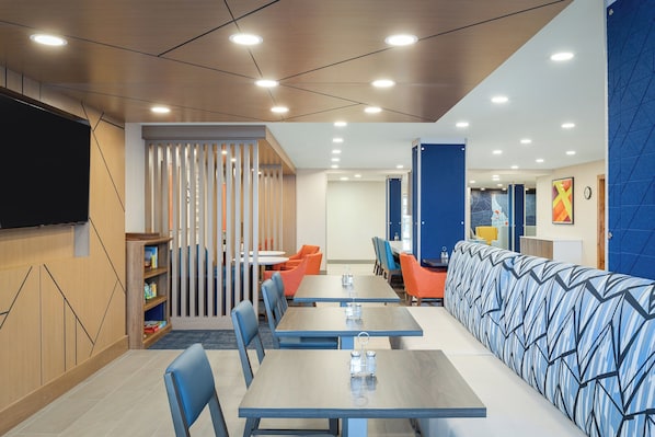 Uma sala de jantar moderna com mesas, cadeiras e um longo banco.