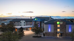 A Holiday Inn Express building with a stone facade and blue lighting, surrounded by trees and a parking lot.
