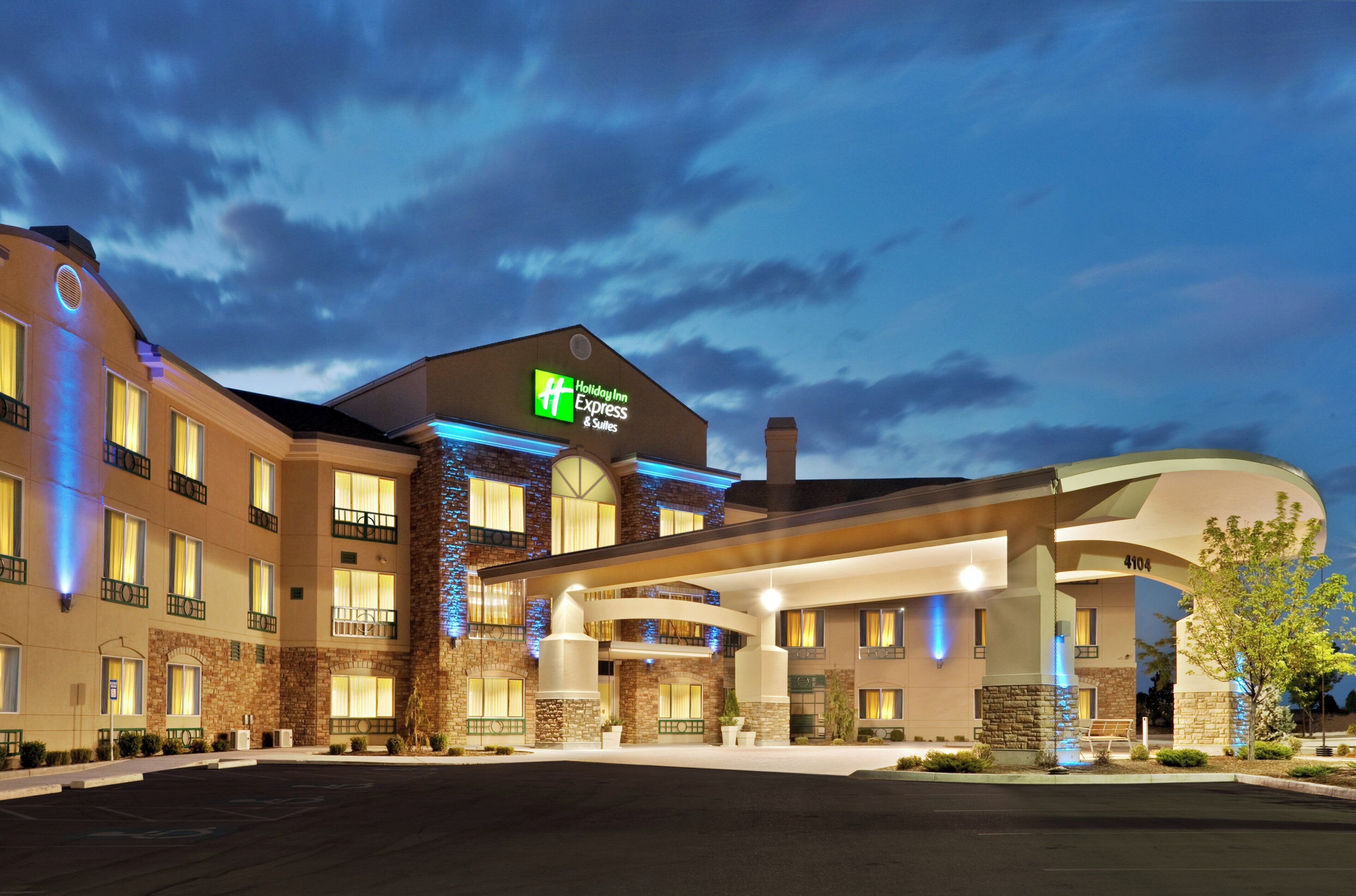Un hotel Holiday Inn Express & Suites con un diseño moderno, que cuenta con una entrada amplia y numerosas ventanas.