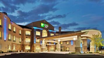 Un hotel Holiday Inn Express & Suites con un diseño moderno, que cuenta con una entrada amplia y numerosas ventanas.