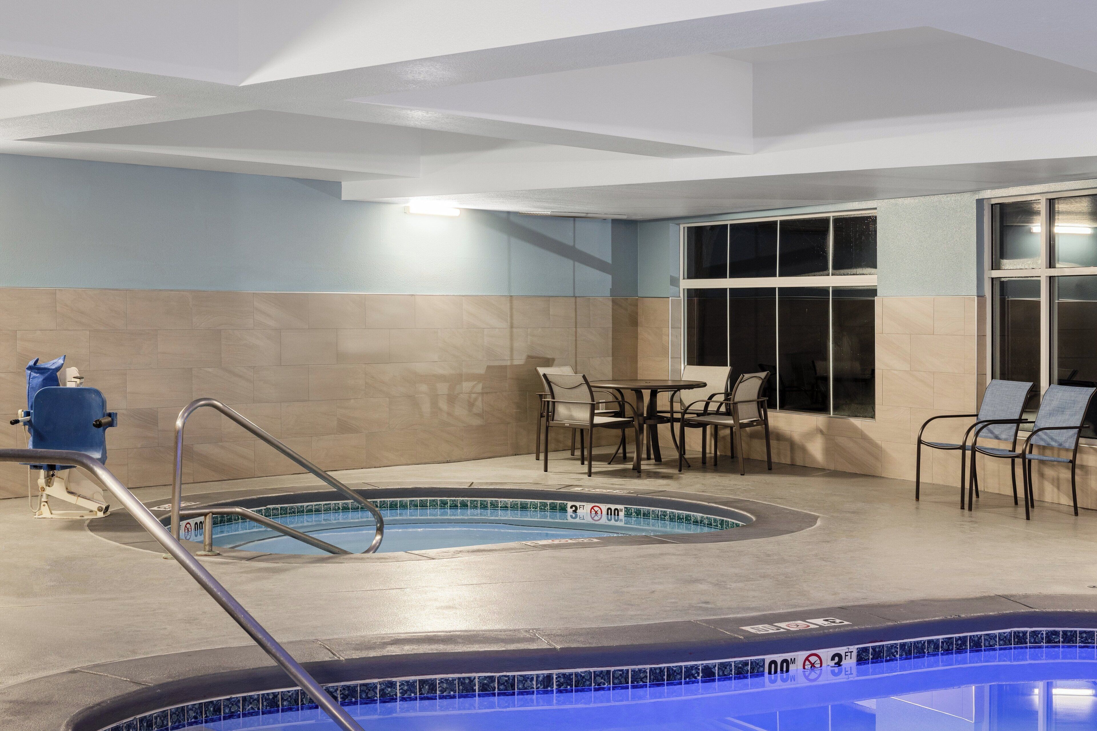 Un espace piscine équipé d’un plongeoir, de chaises longues et d’une table.