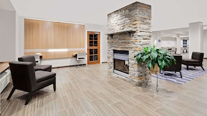 A lobby with a stone fireplace, seating area, and a reception desk. - Microtel Inn & Suites by Wyndham Middletown (Middletown)