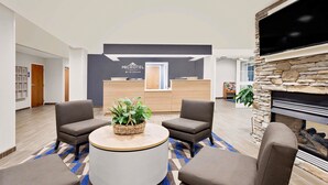 A modern hotel lobby with a reception desk, seating area, and a fireplace. - Microtel Inn & Suites by Wyndham Middletown (Middletown)
