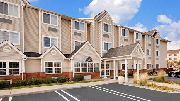 A multi-story hotel with a central courtyard, large windows, and a parking lot. - Microtel Inn & Suites by Wyndham Middletown (Middletown)