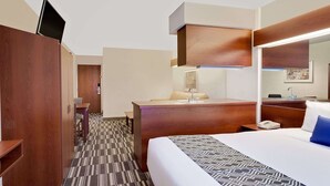A hotel room with a bed, a desk, a chair, a wardrobe, and a bathroom mirror. - Microtel Inn & Suites by Wyndham Middletown (Middletown)