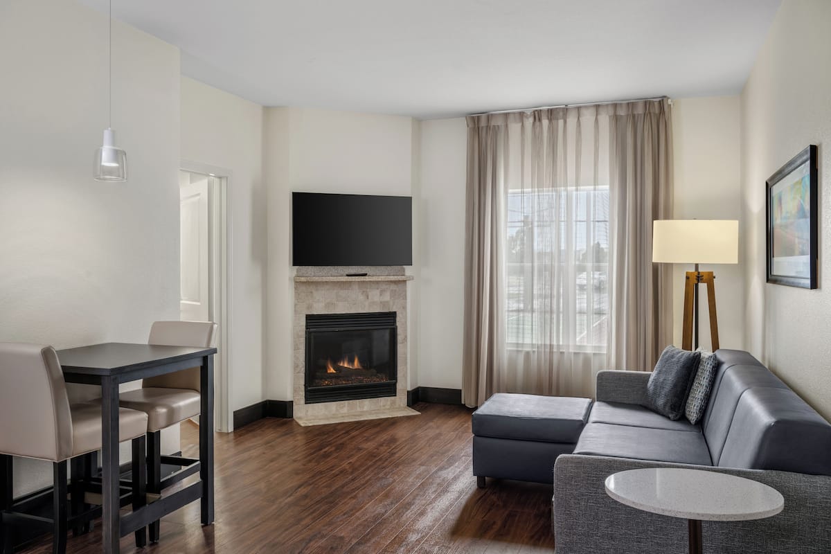 Una sala moderna con chimenea, televisor de pantalla plana, sofá, mesa de comedor y lámpara.