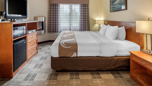 A hotel room with a large bed, a television, a coffee machine, a refrigerator, and a window with curtains. - Quality Inn Kenai (Kenai)