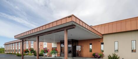 Un edificio moderno con entrada cubierta, ventanas amplias y plantas en macetas.