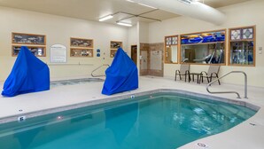 A pool area with two covered chairs, a sign about spa regulations, and a glass-enclosed viewing area. - Quality Inn Kenai (Kenai)