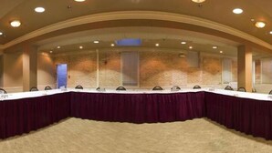 Un salón de conferencias con una mesa larga, sillas y piso alfombrado.