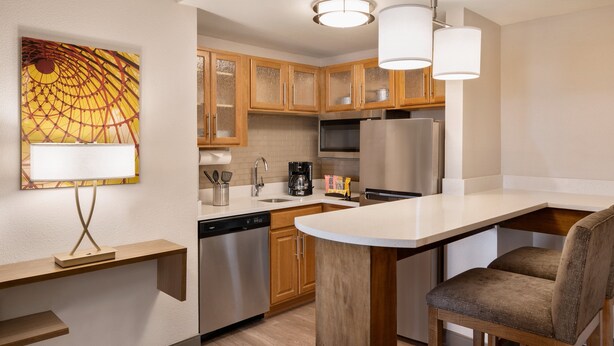 Una cocina moderna con armarios de madera, electrodomésticos de acero inoxidable y una isla central con asientos.