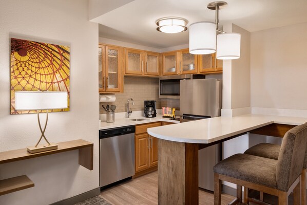 Una cocina moderna con armarios de madera, electrodomésticos de acero inoxidable y una isla central con asientos.