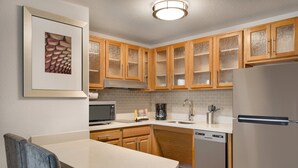 Una cocina moderna con armarios de madera, microondas, cafetera y lavavajillas.