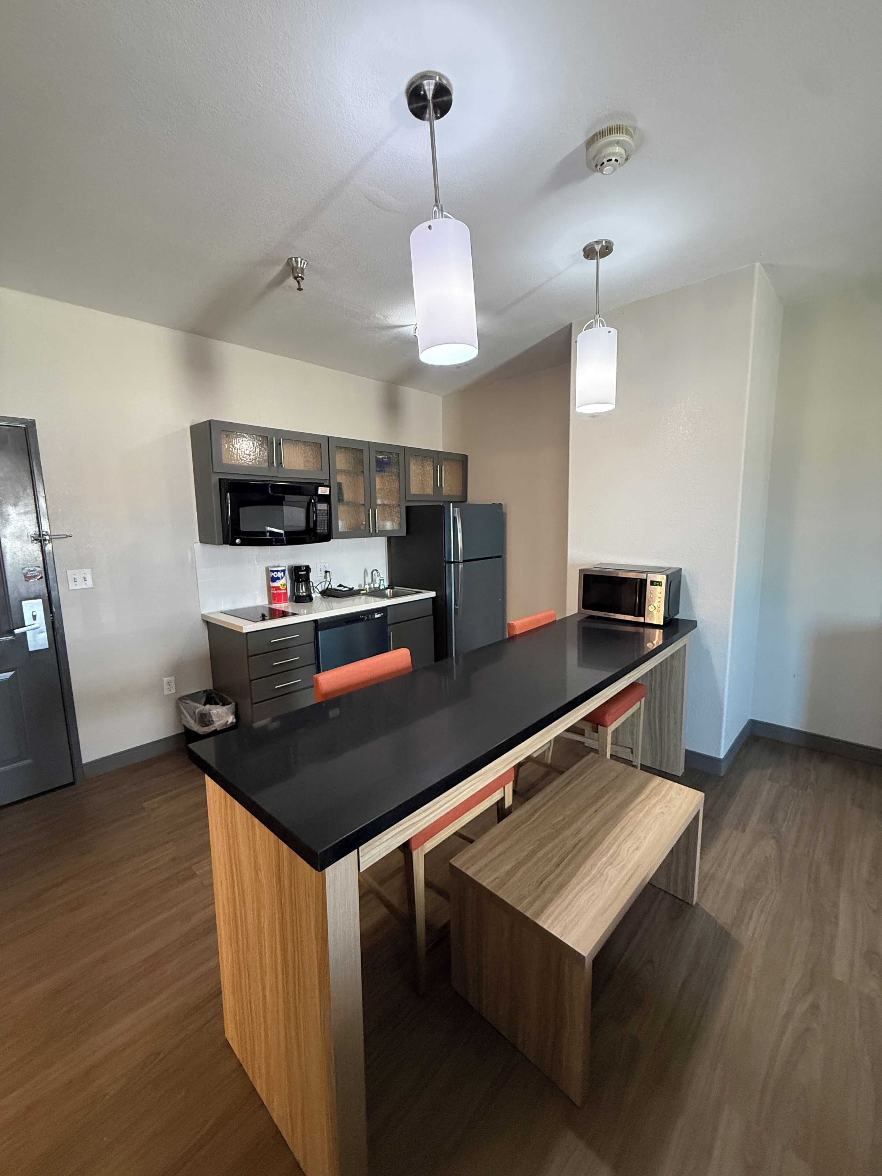 A modern kitchen with a central island, stainless steel appliances, and a pendant light.