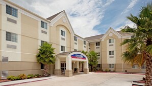 A hotel with a central entrance, multiple windows, and palm trees. - Candlewood Suites Corpus Christi-Spid by IHG (Corpus Christi)