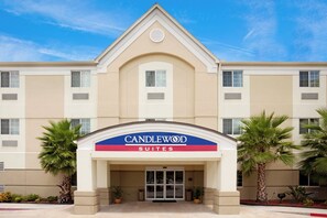 Entrada de un hotel con un cartel que dice 'CANDLEWOOD SUITES'.