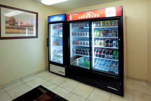 Zona de máquinas expendedoras con dos dispensadores de bebidas, uno etiquetado como 'Candlewood Cupboard' y el otro 'Coca-Cola'.