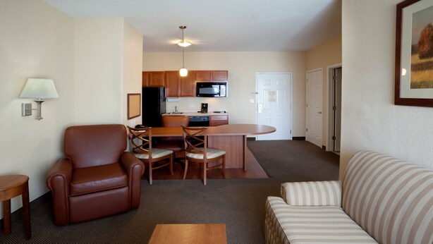 Un espacio habitable compacto con kitchenette, un sillón de cuero marrón, un sofá a rayas y una mesa de centro de madera.