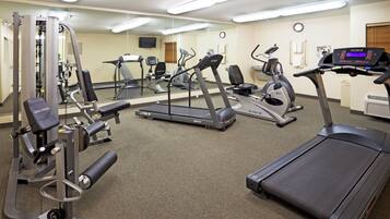 A gym with various exercise equipment including treadmills, elliptical machines, and weight machines.