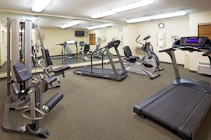 Un gimnasio con equipos de ejercicio variados, incluyendo cintas de correr, elípticas y máquinas de pesas.