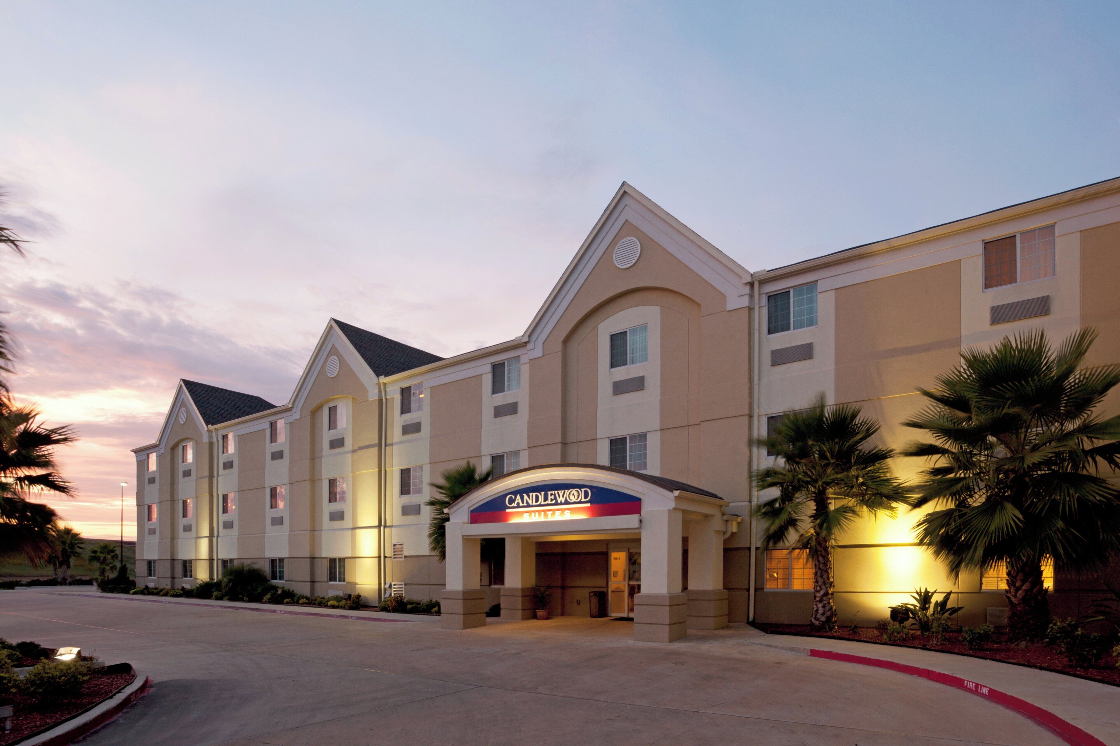 A hotel with a prominent 'CANDLEWOOD' sign, multiple floors, and a fire lane on the street.