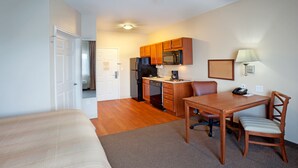 A compact hotel room with a kitchenette, a dining area, and a separate sleeping area. - Candlewood Suites Corpus Christi-Spid by IHG (Corpus Christi)