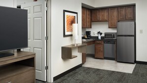 A modern kitchen with wooden cabinets, a stainless steel refrigerator, a microwave, and a coffee maker.