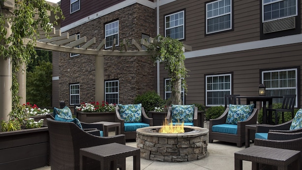 An outdoor patio with wicker furniture, a stone fire pit, and a pergola.