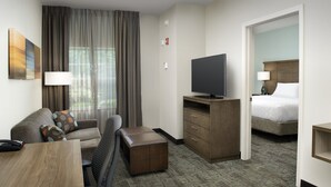 A hotel room with a sofa, a TV, a desk, and a bed.