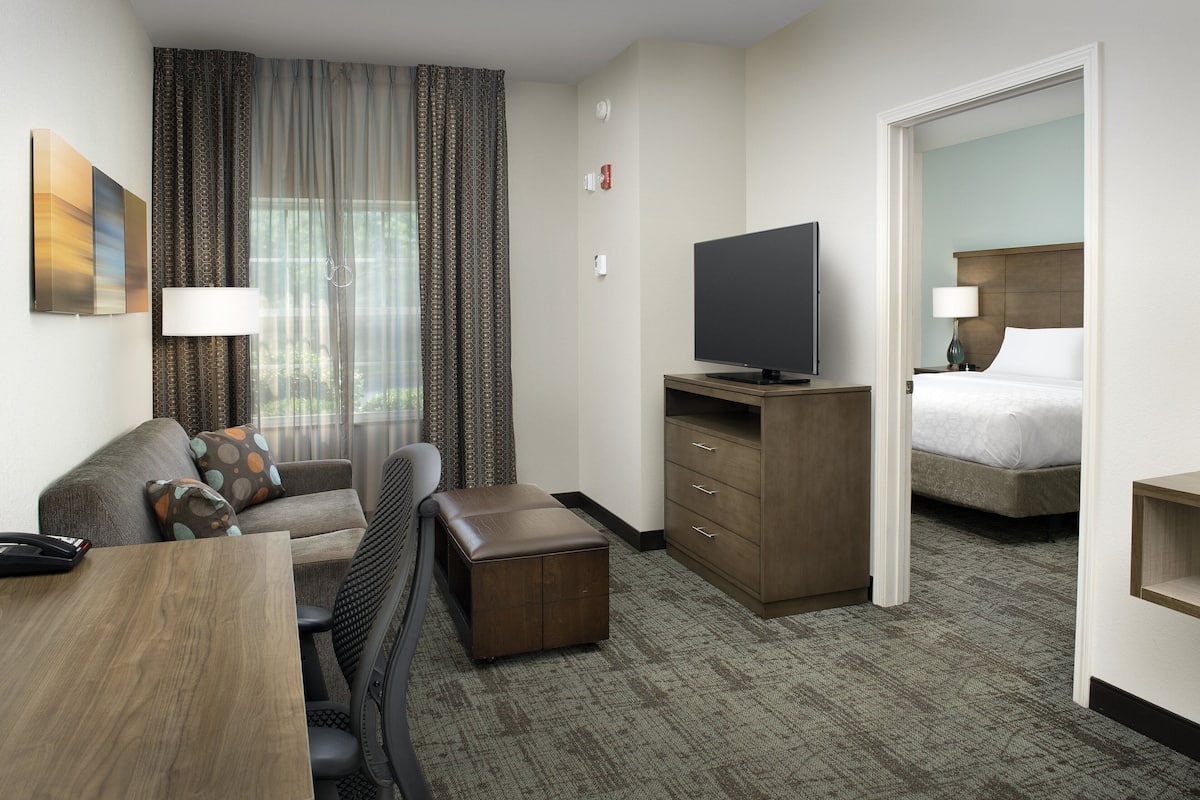 A hotel room with a sofa, a TV, a desk, and a bed.