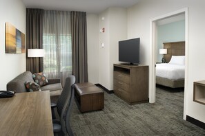 Une chambre d’hôtel avec un canapé, une télévision, un bureau et un lit.