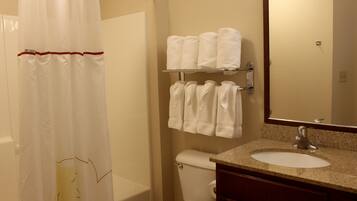 A bathroom with a shower curtain, a toilet, a sink, and a towel rack with towels.