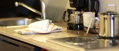 A kitchen counter with a coffee maker, a kettle, and a dish rack.