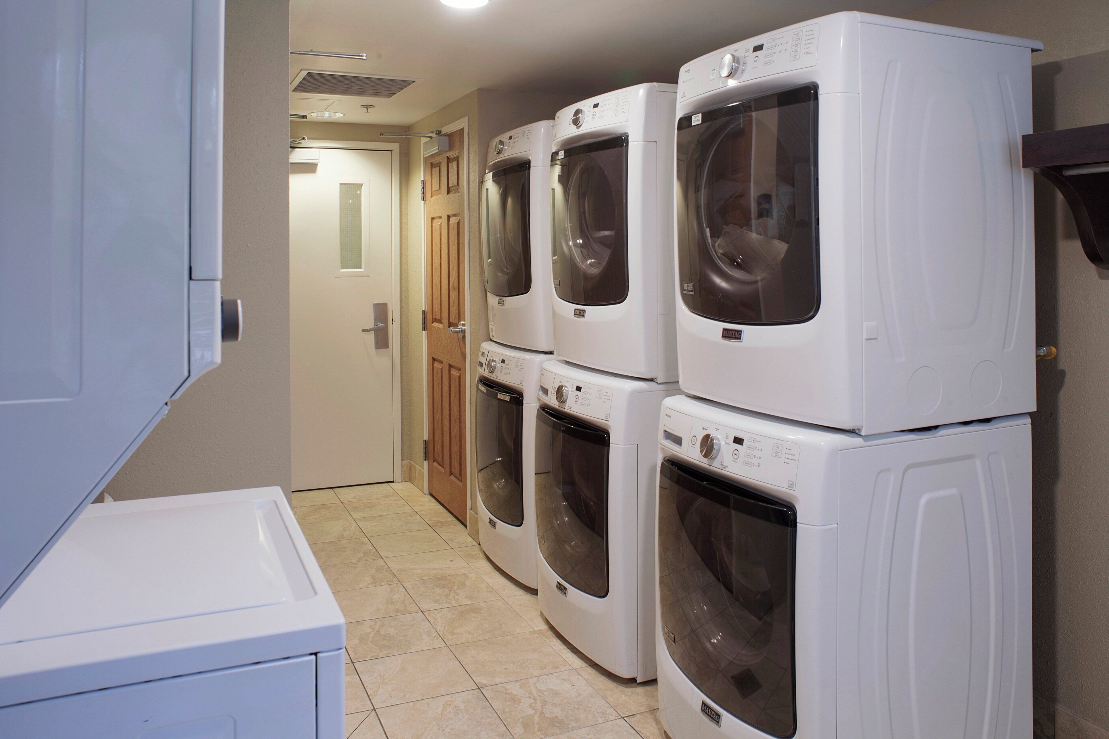 A laundry room with four stacked front-loading washing machines.