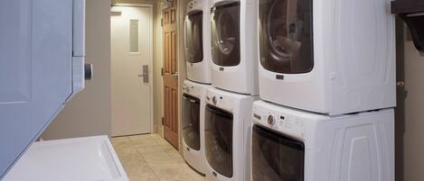 A laundry room with four stacked front-loading washing machines.