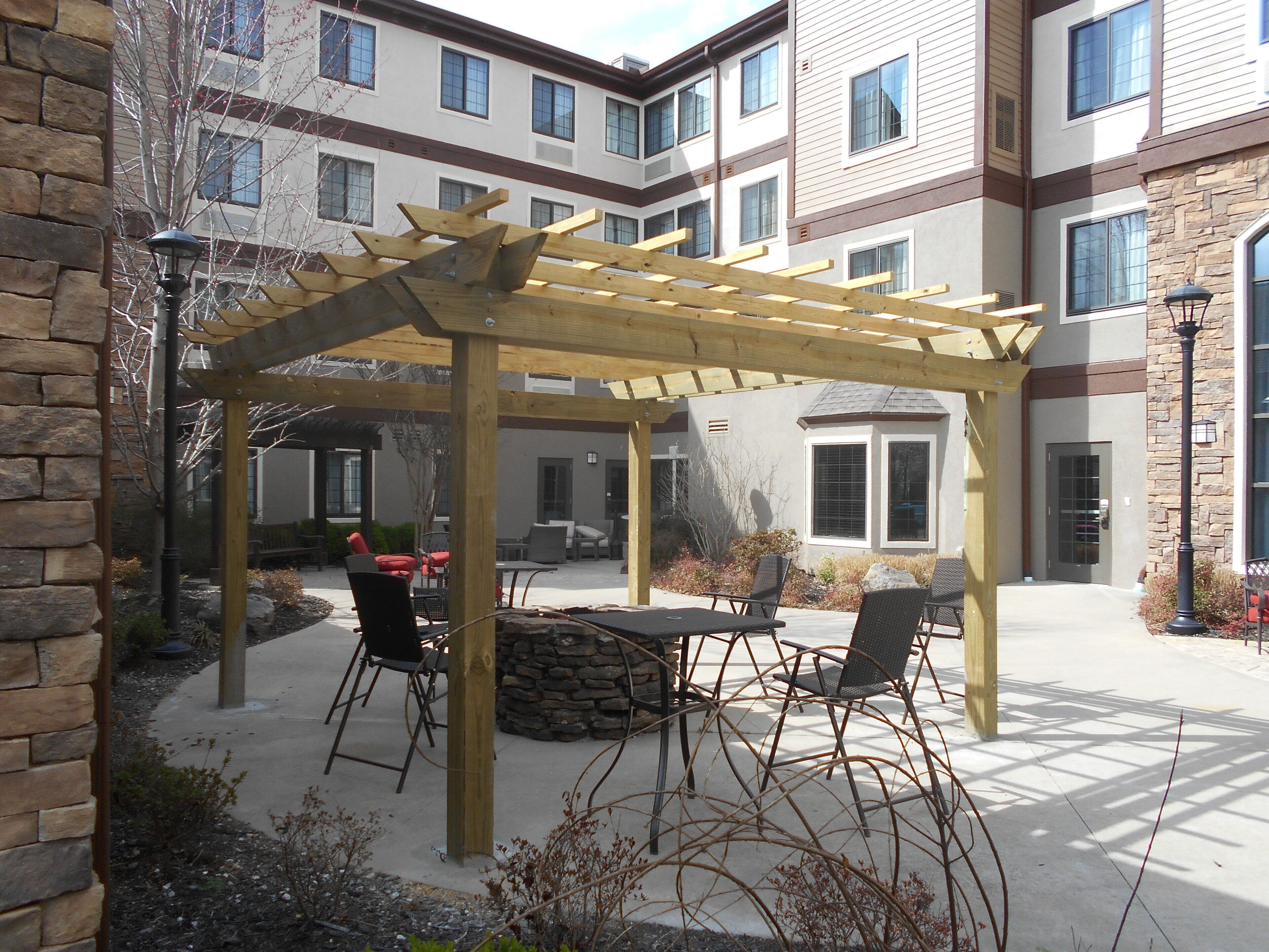 Une terrasse extérieure dotée d’une pergola, de sièges et d’une cheminée en pierre.