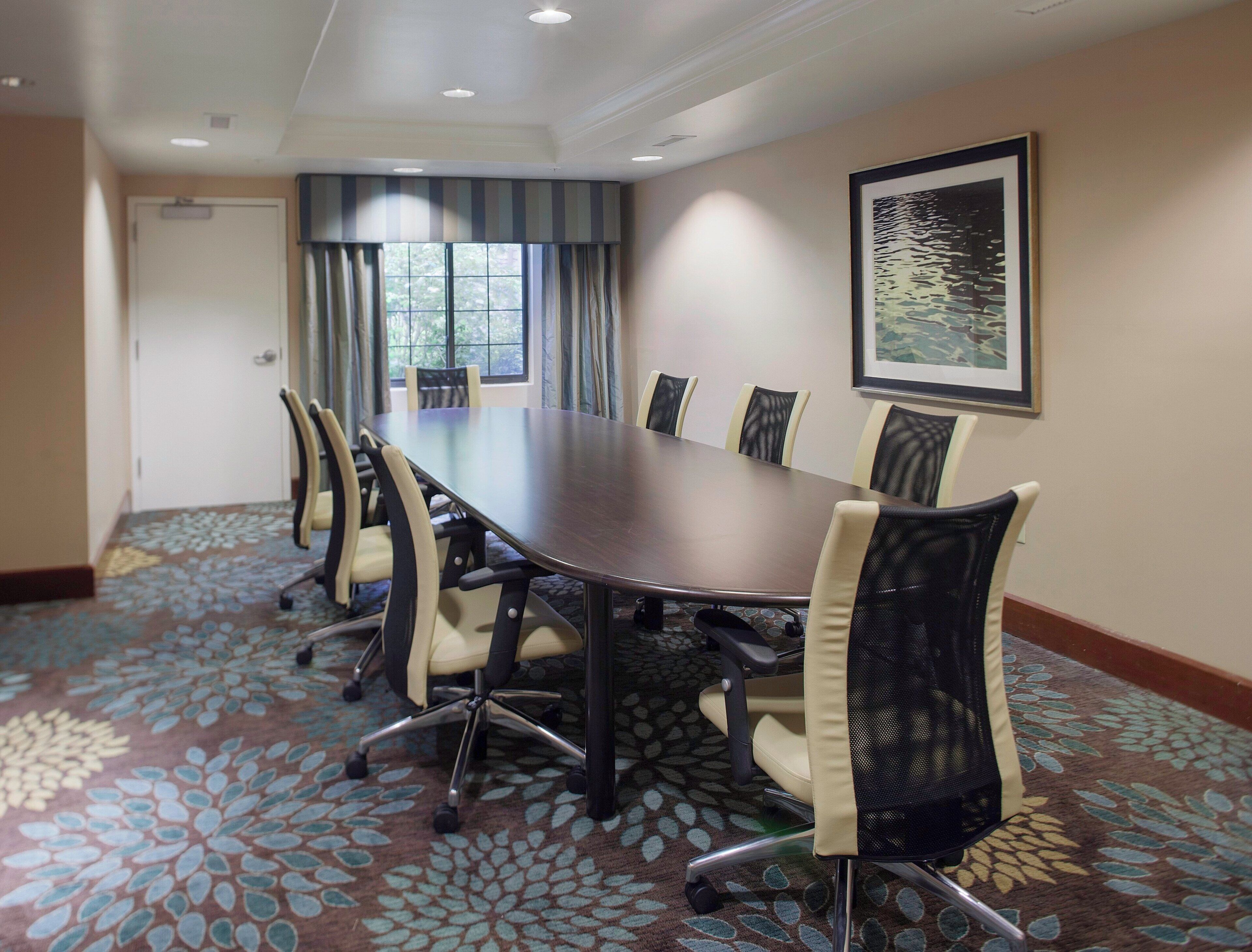 Un salón de conferencias con una gran mesa, seis sillas y un cuadro en la pared.