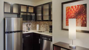 Una cocina moderna con electrodomésticos de acero inoxidable, muebles oscuros, salpicadero de azulejos y una obra de arte floral enmarcada en la pared.