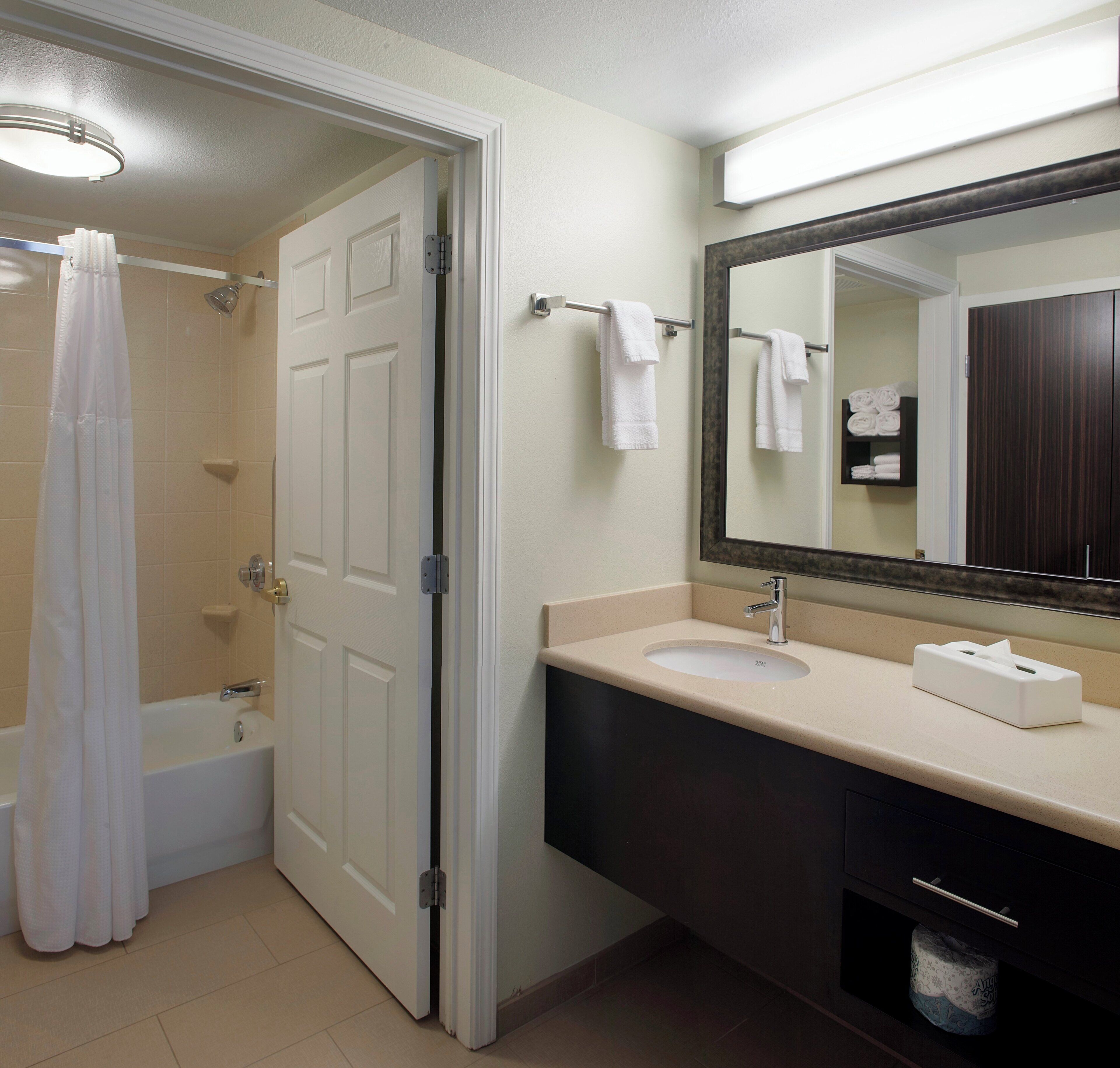 Un baño con bañera, lavabo, espejo y perchero para toallas.