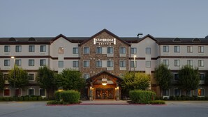 A Staybridge Suites hotel with a symmetrical facade, multiple windows, and a central entrance with a welcoming archway. - Staybridge Suites Fayetteville/Univ Of Arkansas by IHG (Fayetteville)